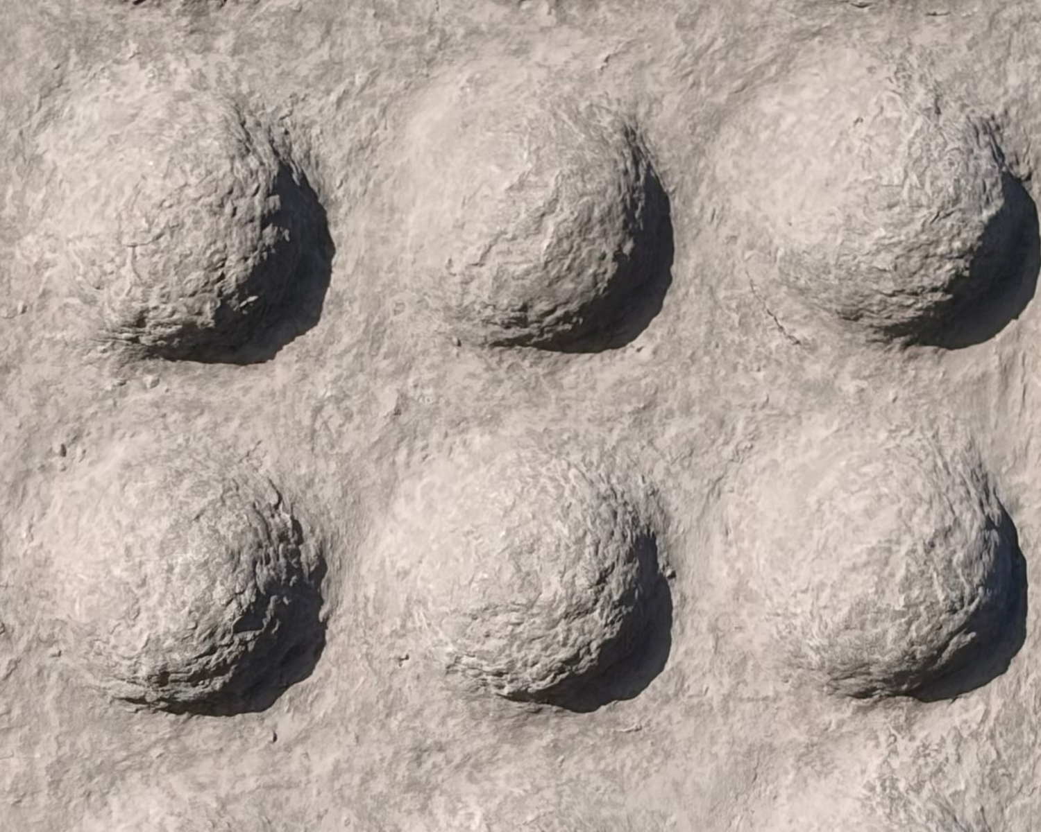 A rectangular gray textured panel with a grid of raised circular bumps, photographed outdoors among rocks and gravel.